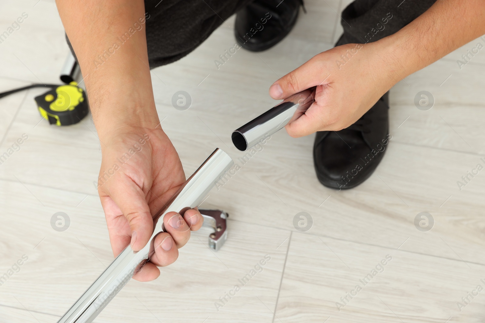 Photo of Worker installing new metal pipes indoors, closeup