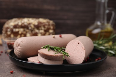 Photo of Delicious liver sausages with rosemary on brown textured table