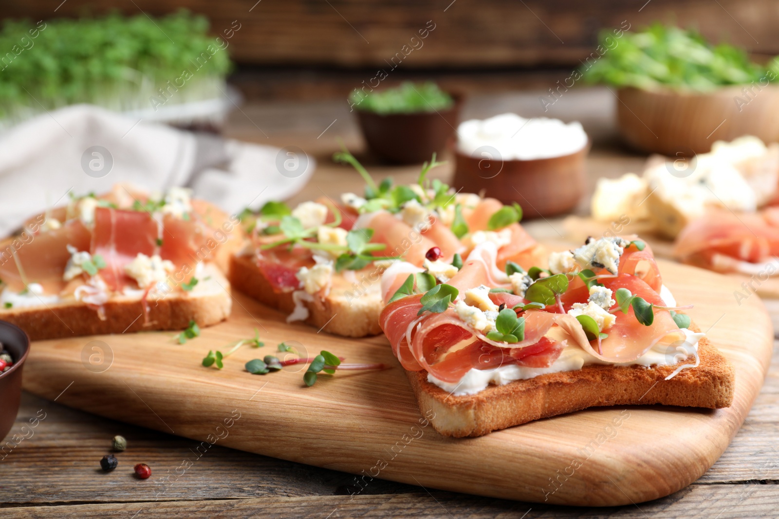 Photo of Delicious sandwiches with prosciutto, cheese and microgreens on wooden table, closeup