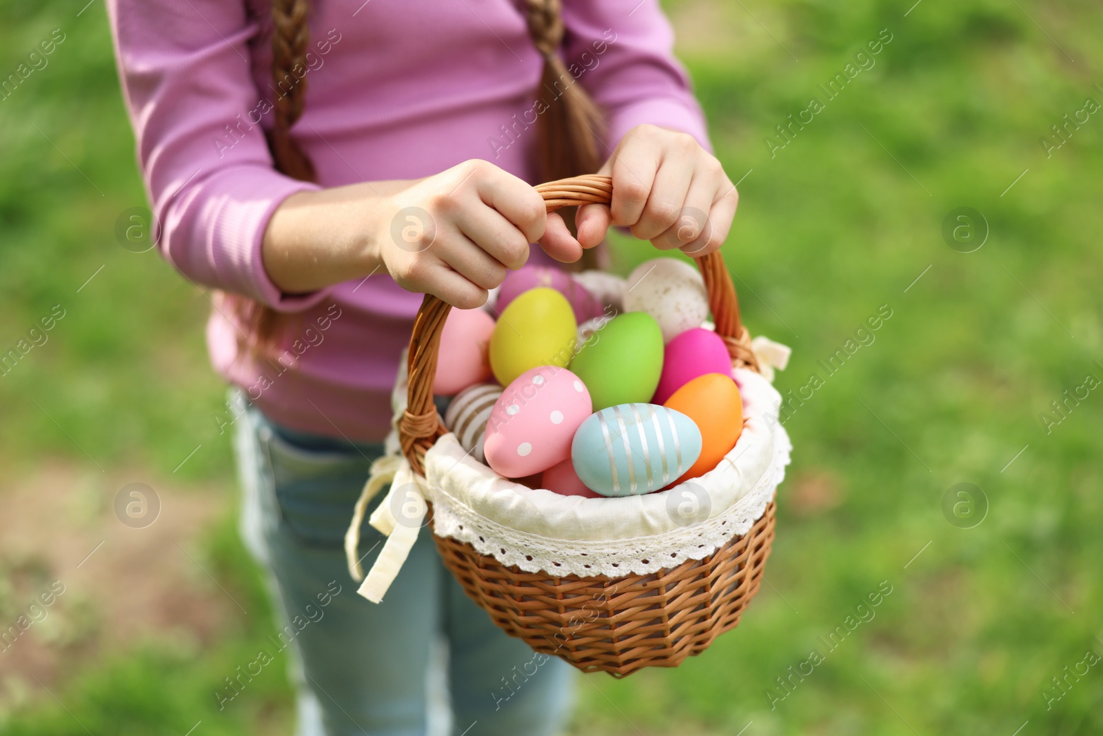 Photo of Easter celebration. Little girl holding basket with painted eggs outdoors, closeup