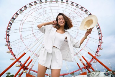 Photo of Beautiful young woman near Ferris wheel outdoors, low angle view