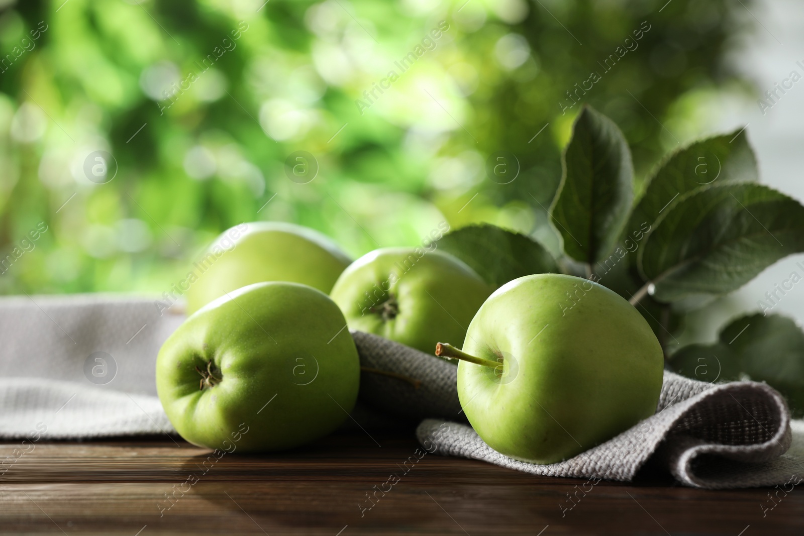 Photo of Fresh ripe green apples and leaves on wooden table outdoors