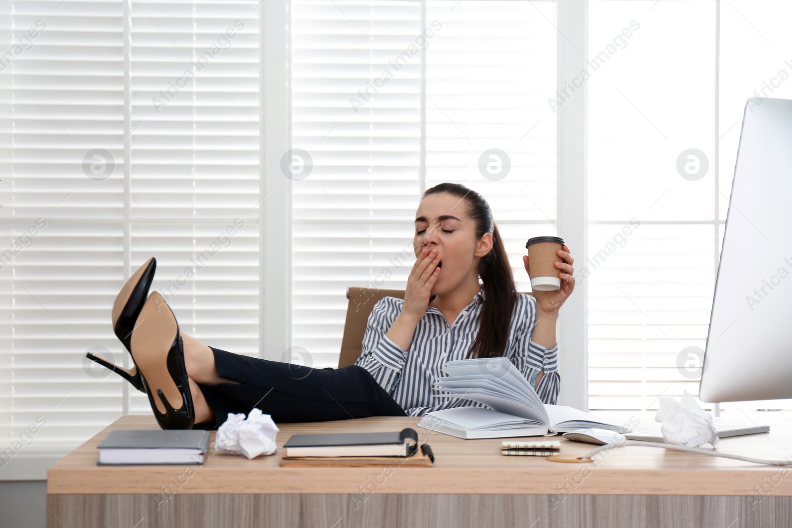 Photo of Lazy employee yawning at table in office