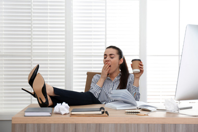 Lazy employee yawning at table in office