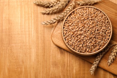 Photo of Wheat grains with spikelets on wooden table, flat lay. Space for text