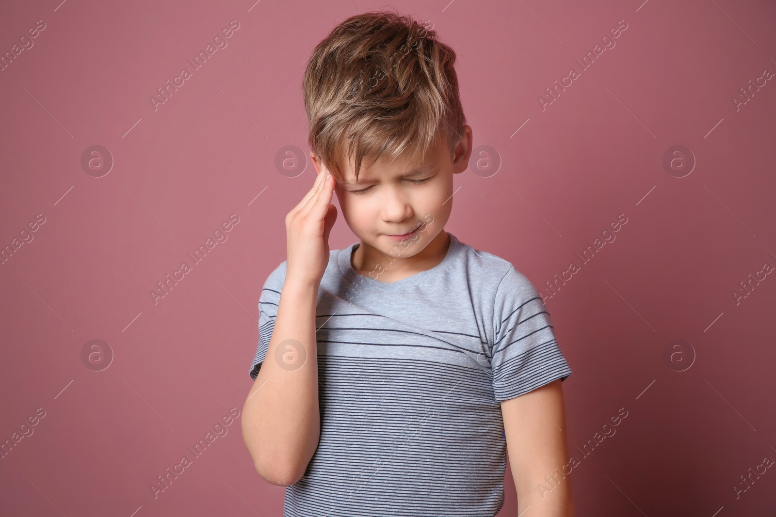 Photo of Little boy suffering from headache on color background