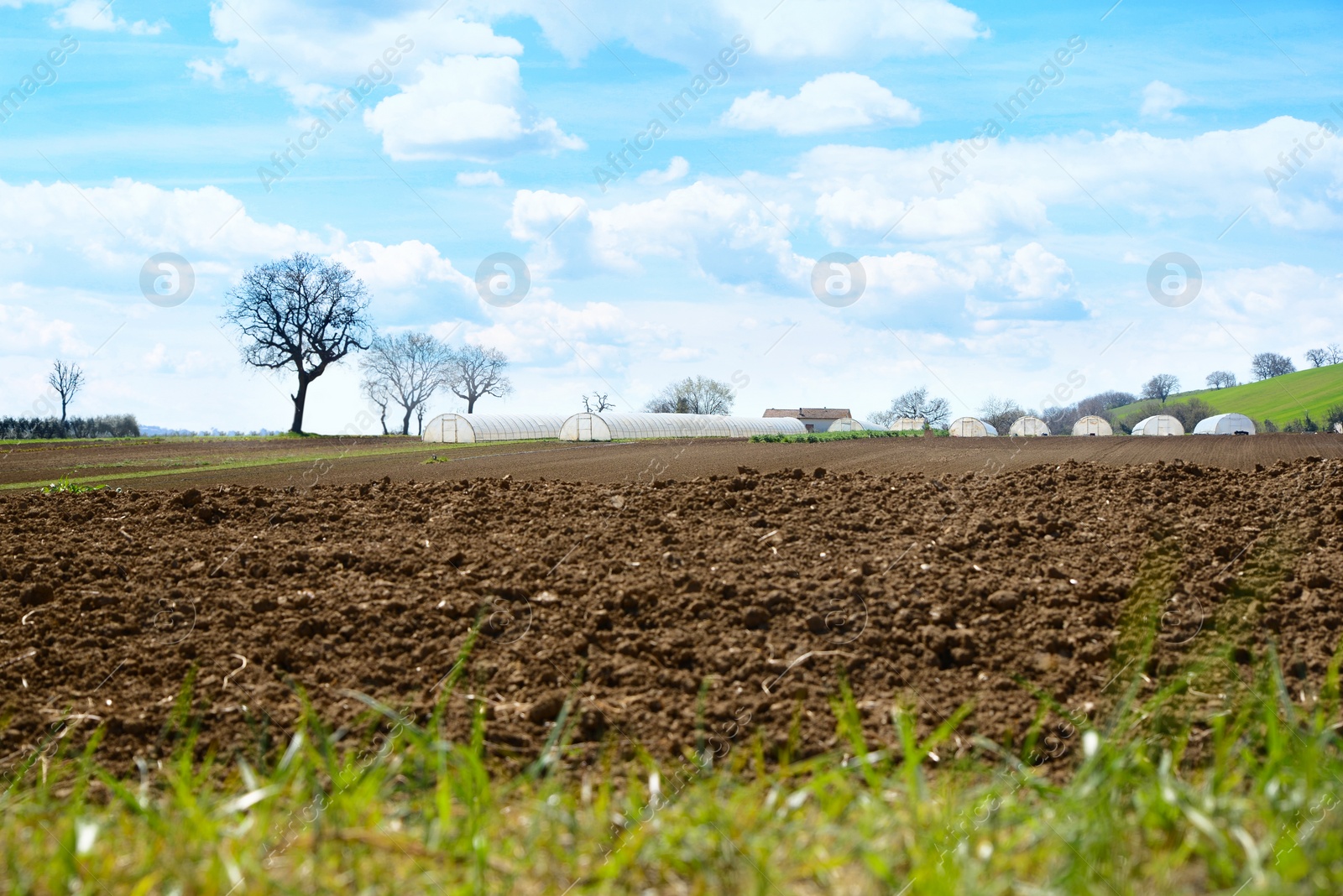 Photo of Many greenhouses near plowed field in countryside