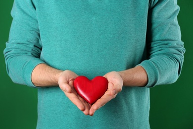 Photo of Man holding decorative heart on color background, closeup