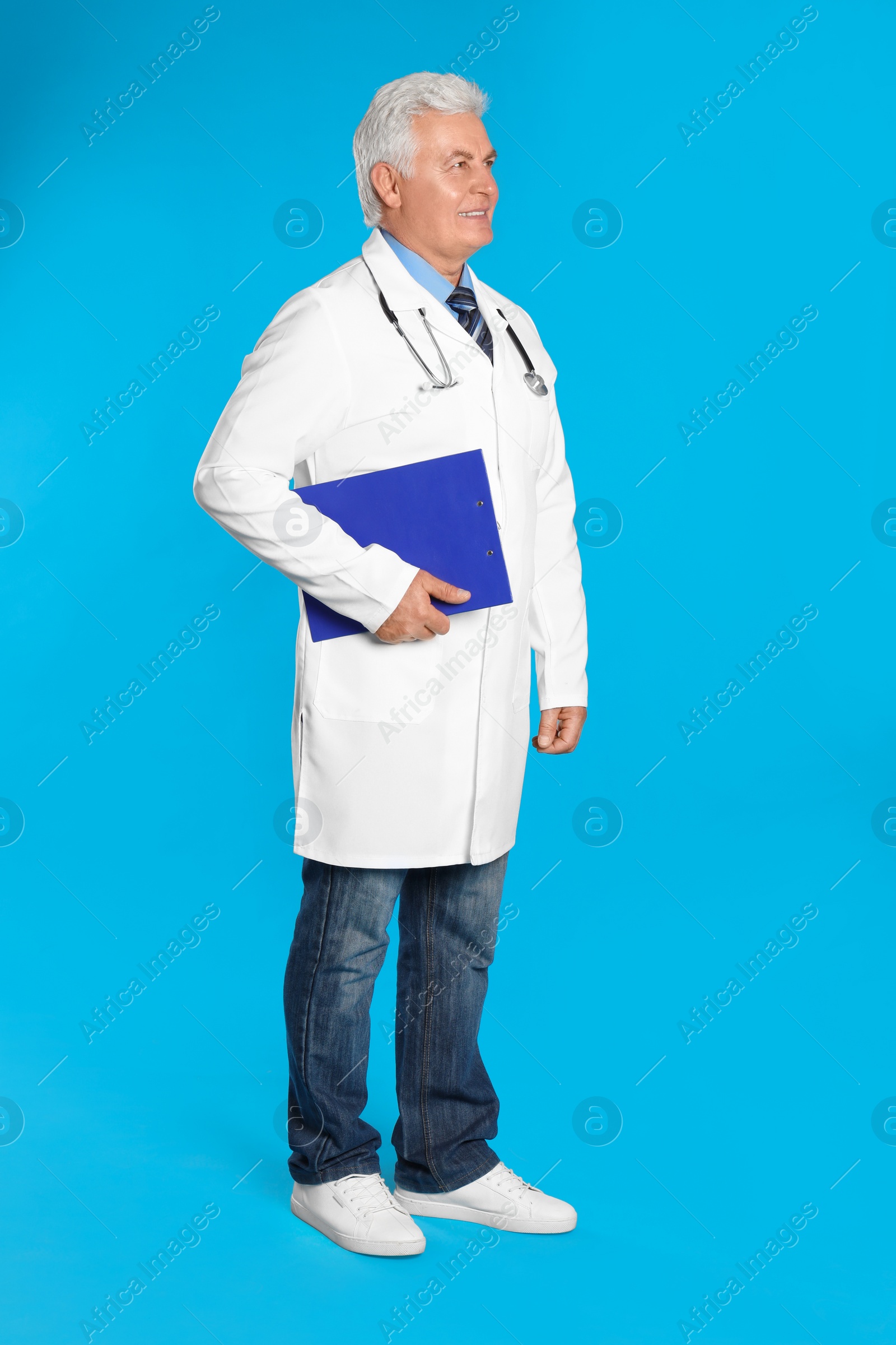 Photo of Senior doctor with clipboard on light blue background