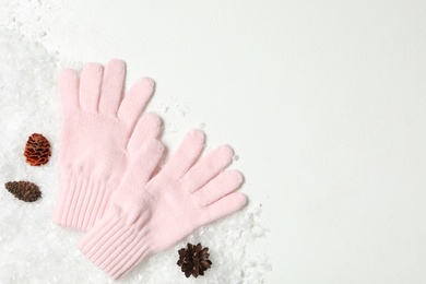 Photo of Stylish pink woolen gloves, fir cones and artificial snow on white table, top view. Space for text