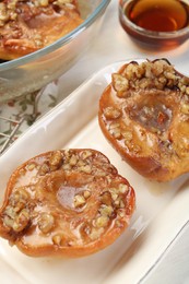 Delicious quinces baked with honey and walnuts on white table, closeup