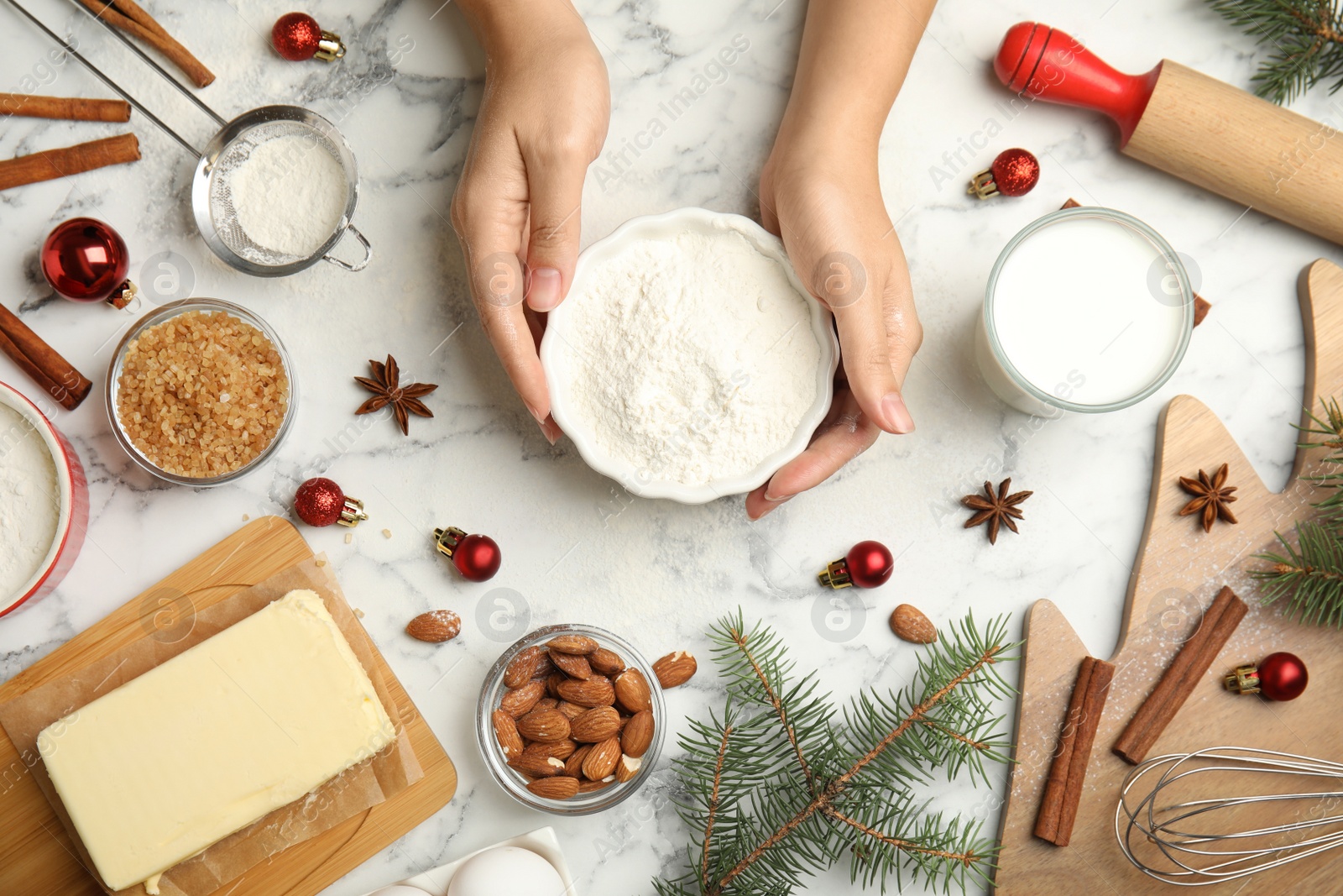 Photo of Woman cooking traditional Christmas cake at white marble table with ingredients, top view