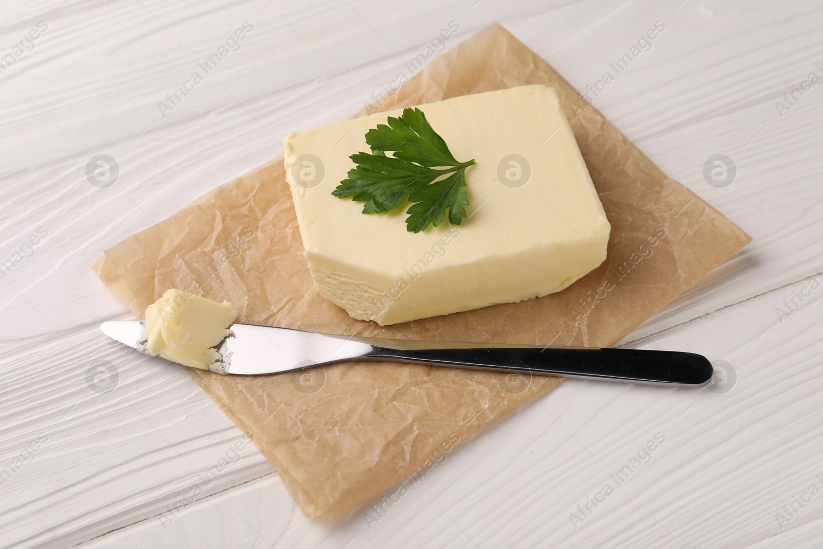 Photo of Tasty butter and knife on white wooden table