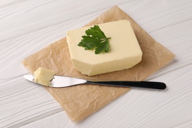 Tasty butter and knife on white wooden table