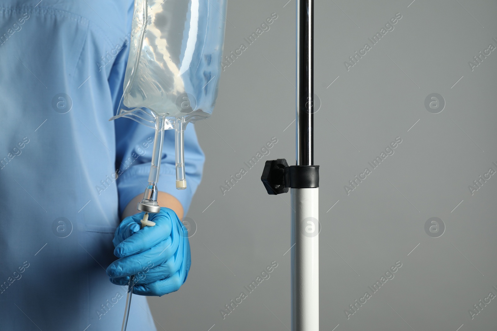 Photo of Nurse with IV infusion set on grey background, closeup