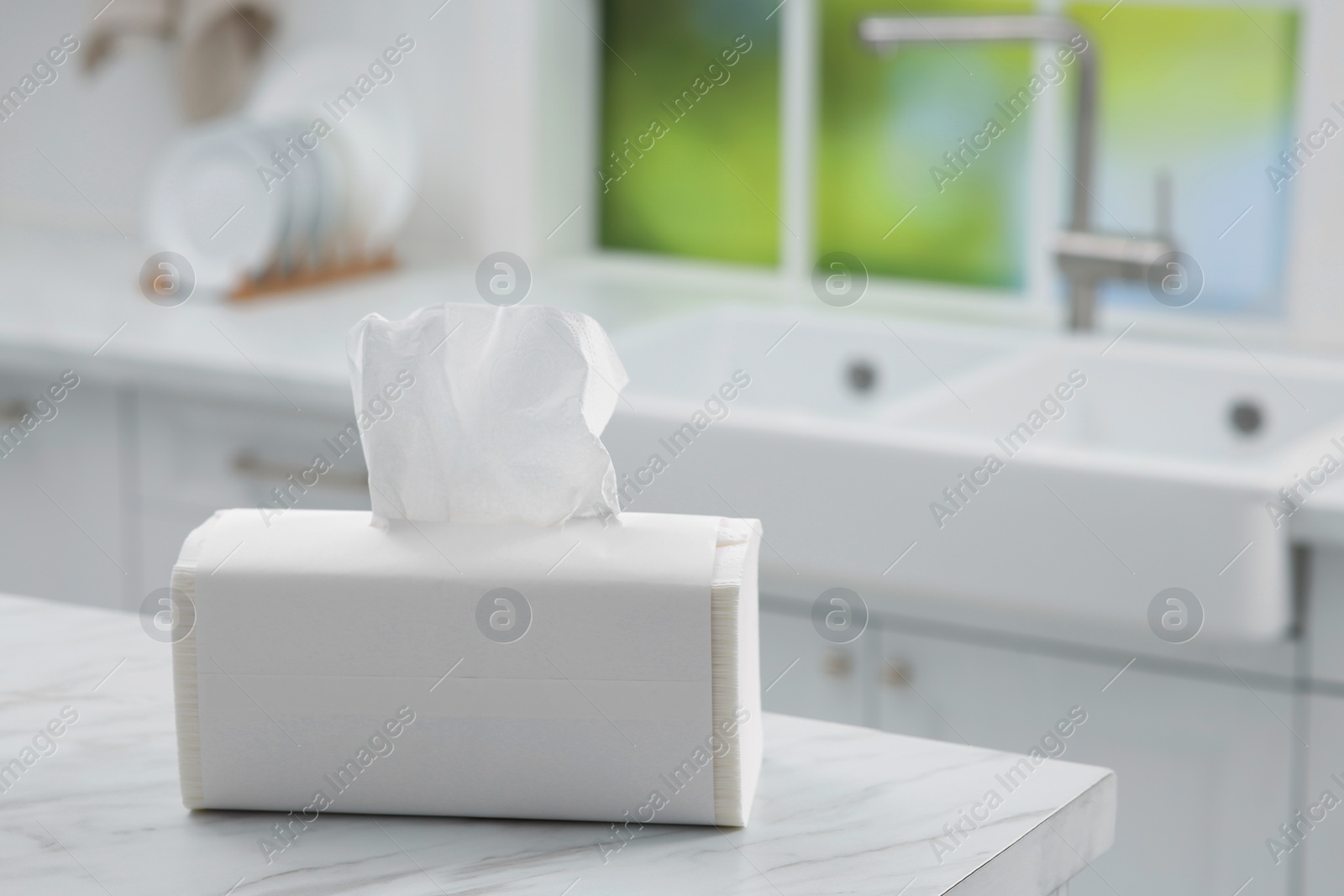 Photo of Package of paper towels on white table in kitchen. Space for text