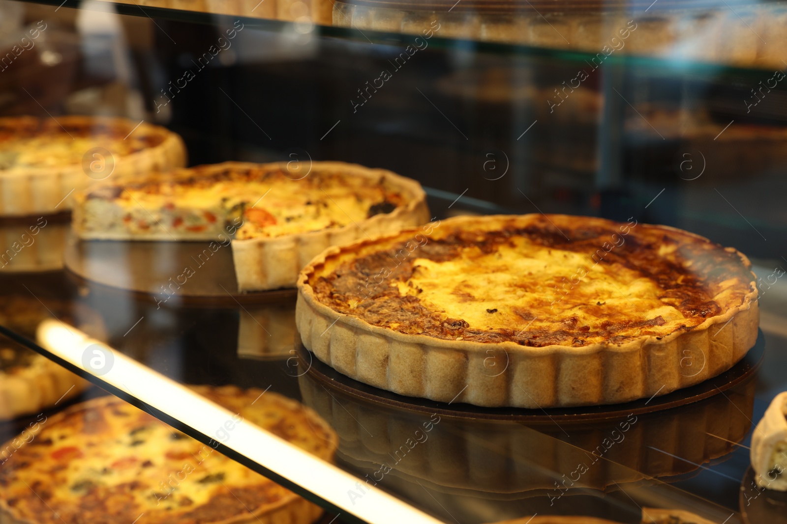 Photo of Different delicious quiches on counter in bakery shop, closeup. Space for text