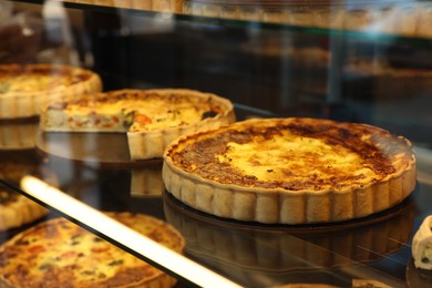 Photo of Different delicious quiches on counter in bakery shop, closeup. Space for text