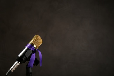 Photo of Microphone with purple awareness ribbon on dark background, space for text