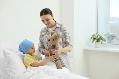 Childhood cancer. Mother and daughter with toy bear in hospital