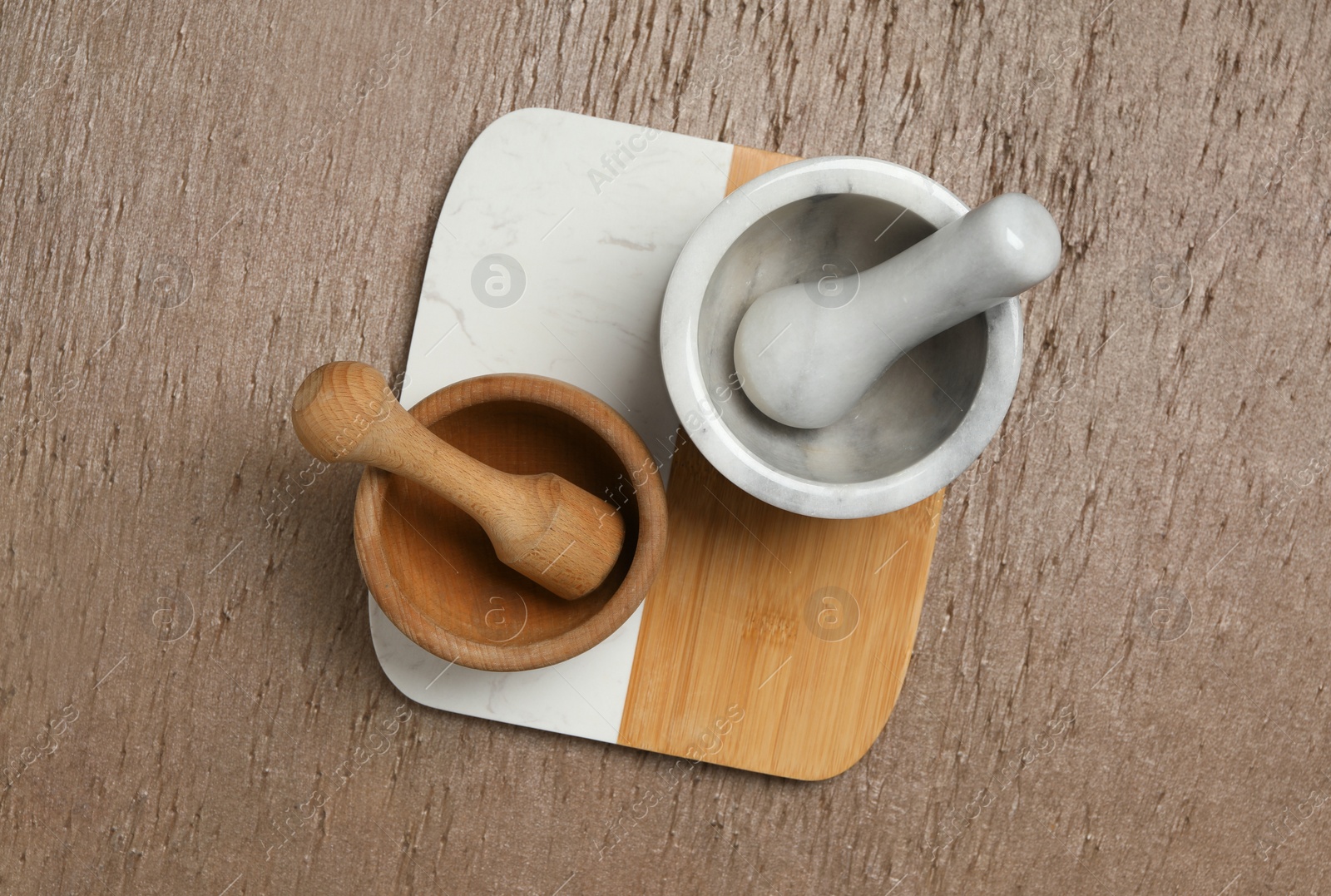 Photo of Clean mortars with pestles on wooden table, top view. Cooking utensils