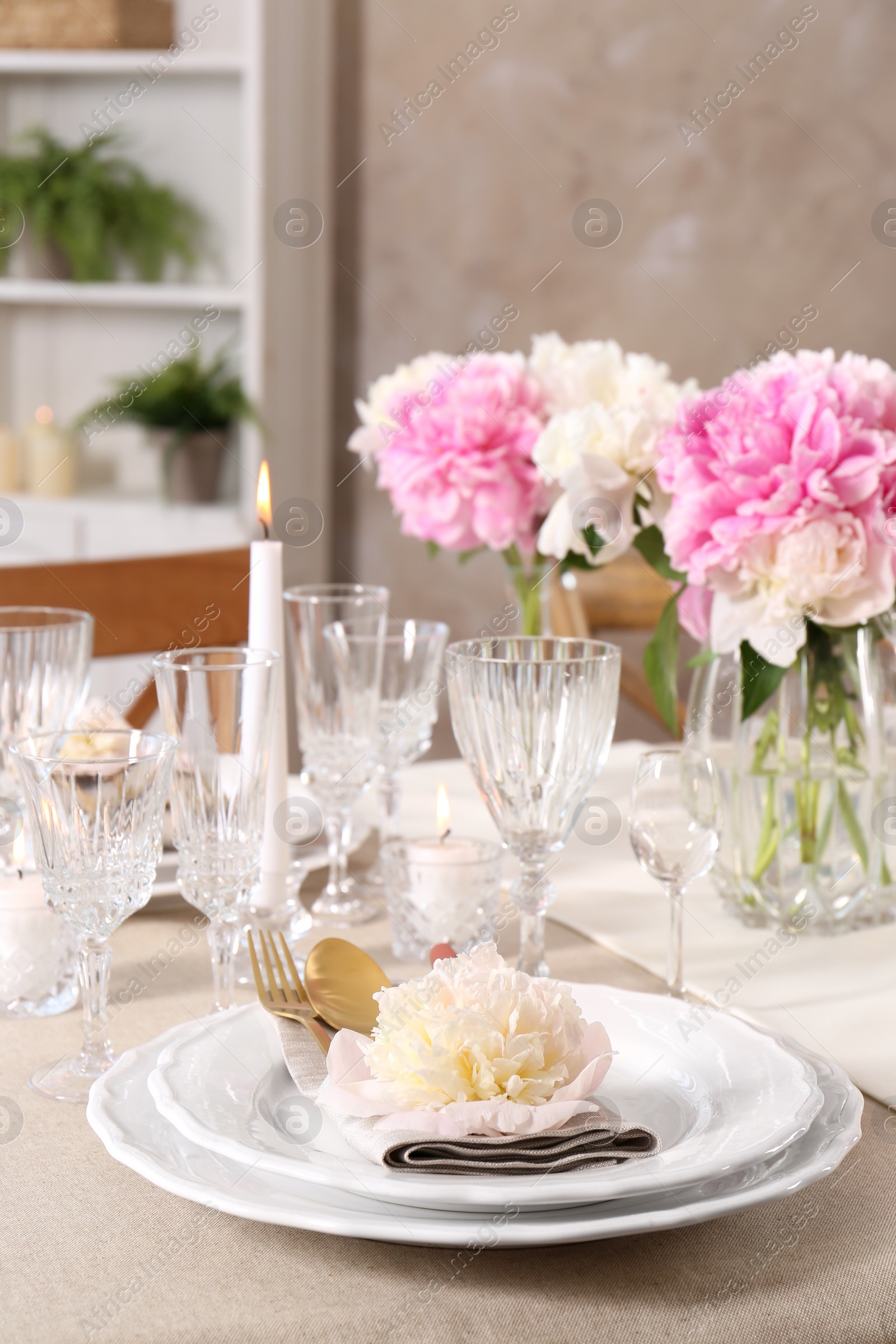 Photo of Stylish table setting with beautiful peonies and burning candles indoors. Space for text