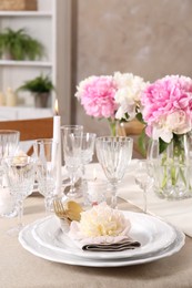 Photo of Stylish table setting with beautiful peonies and burning candles indoors. Space for text