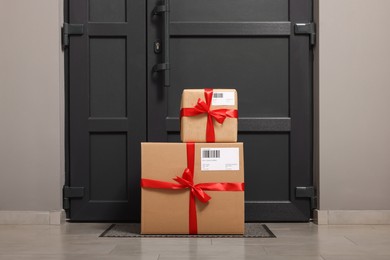 Photo of Christmas gift boxes on floor near door. Sending present by mail