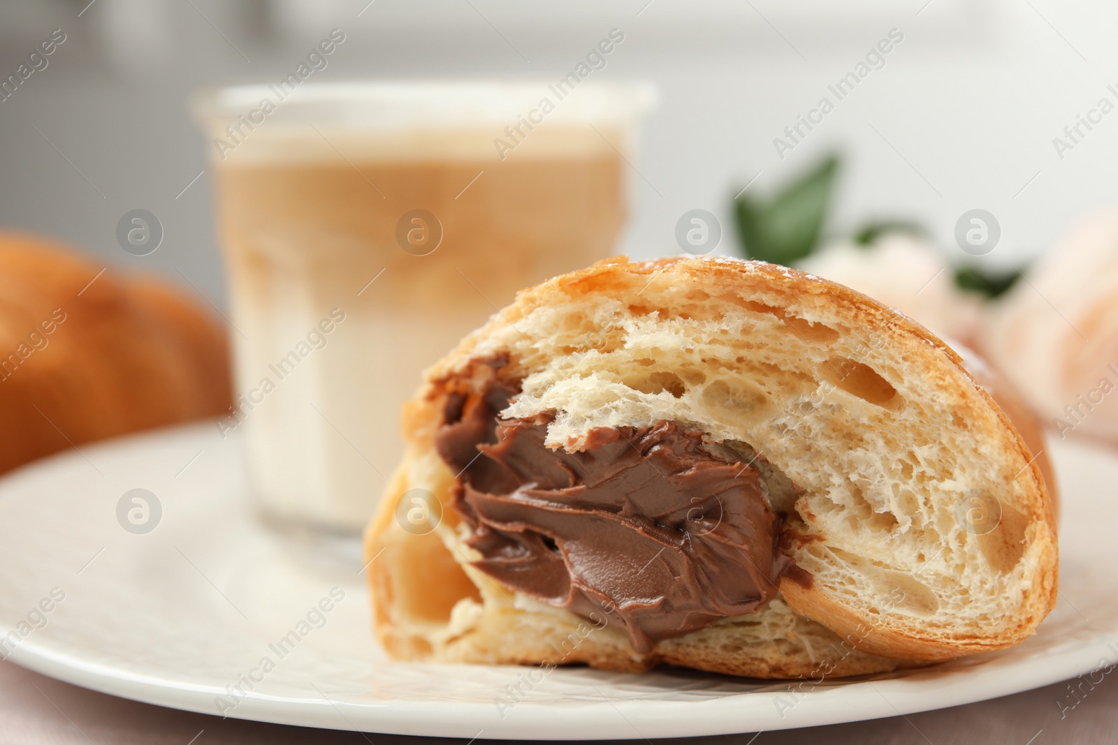 Photo of Half of tasty croissant with chocolate on plate, closeup. Space for text