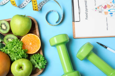 Photo of Fruits, dumbbells, measuring tape and list of products on light blue background, flat lay. Visiting nutritionist