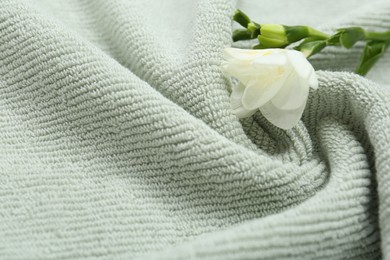 Photo of Freesia flower on soft green towel, closeup. Space for text