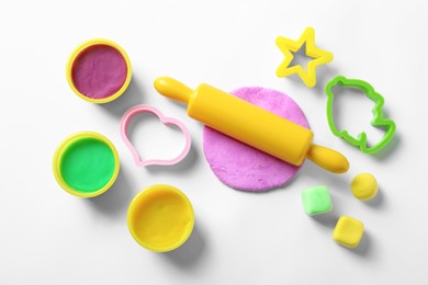 Set of tools and color play dough on white background, top view