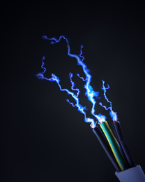 Image of Sparking cables on black background, closeup. Electrician's supply