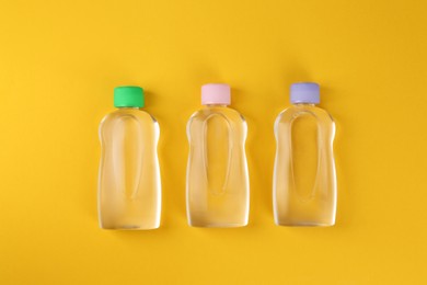 Photo of Bottles with baby oil on orange background, flat lay