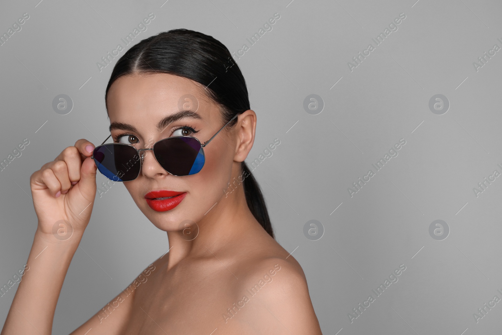 Photo of Attractive woman wearing fashionable sunglasses against grey background. Space for text