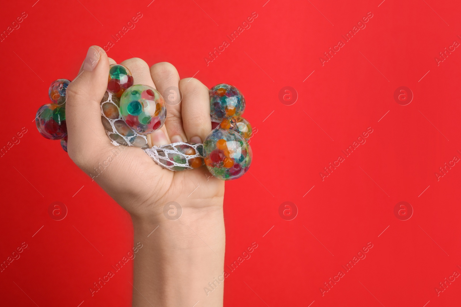 Photo of Woman squeezing colorful slime on red background, closeup. Antistress toy