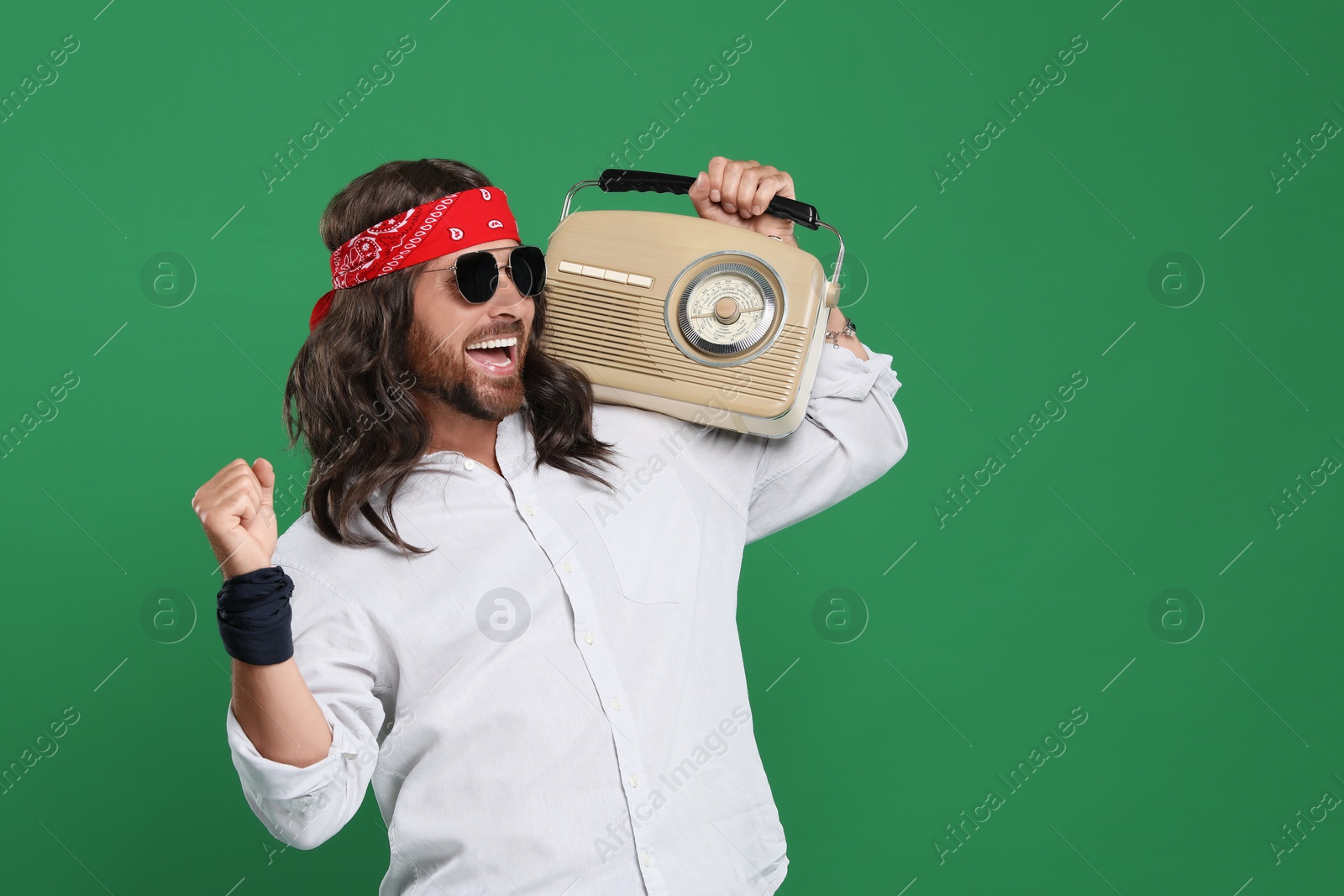 Photo of Stylish hippie man in sunglasses with retro radio receiver on green background