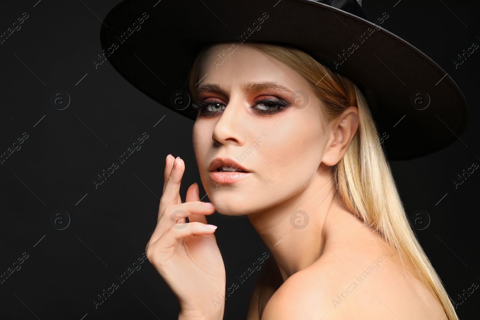 Photo of Witch in black hat on dark background. Scary fantasy character