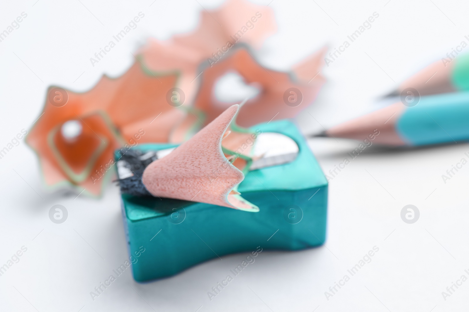 Photo of Pencils, sharpener and shavings on white background, closeup