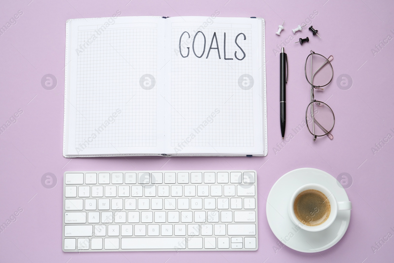 Photo of Flat lay composition with office stationery on violet background. Word Goals in notebook