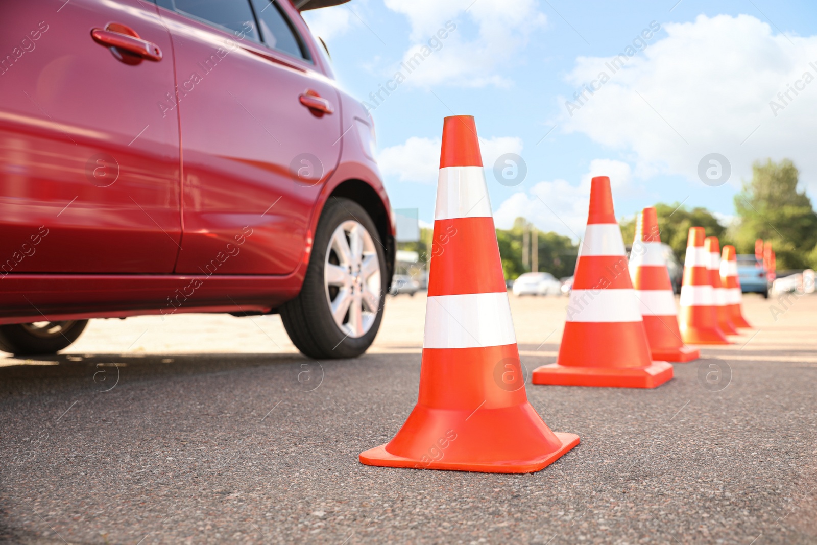 Photo of Traffic cones near red car outdoors. Driving school exam