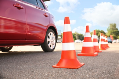 Traffic cones near red car outdoors. Driving school exam