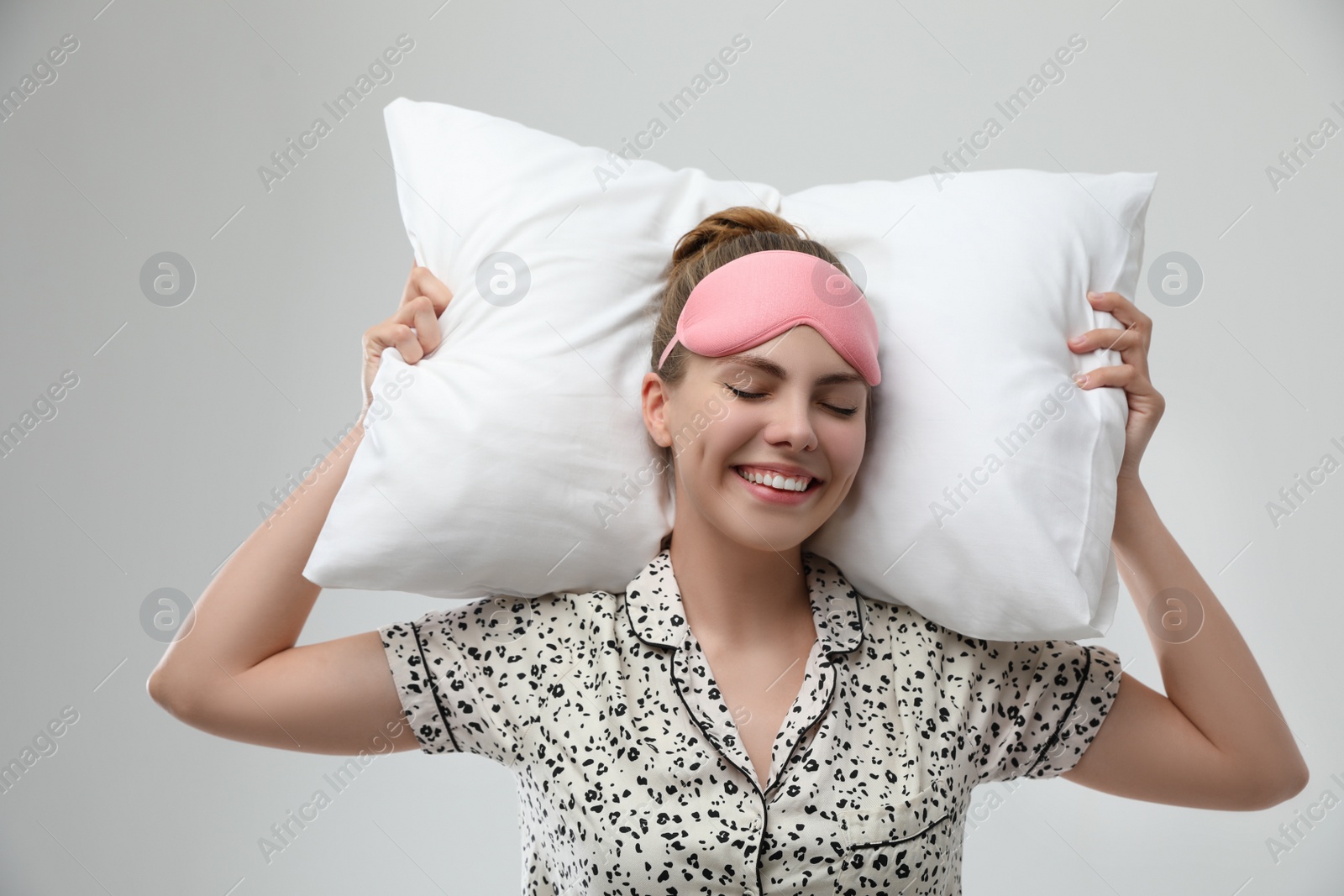 Photo of Beautiful woman with pillow on light grey background. Bedtime