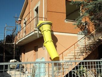 Photo of Building with yellow rubble chute outdoors on sunny day