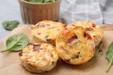 Photo of Delicious egg muffins with cheese and bacon on parchment paper, closeup