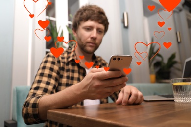 Man visiting dating site via smartphone in cafe