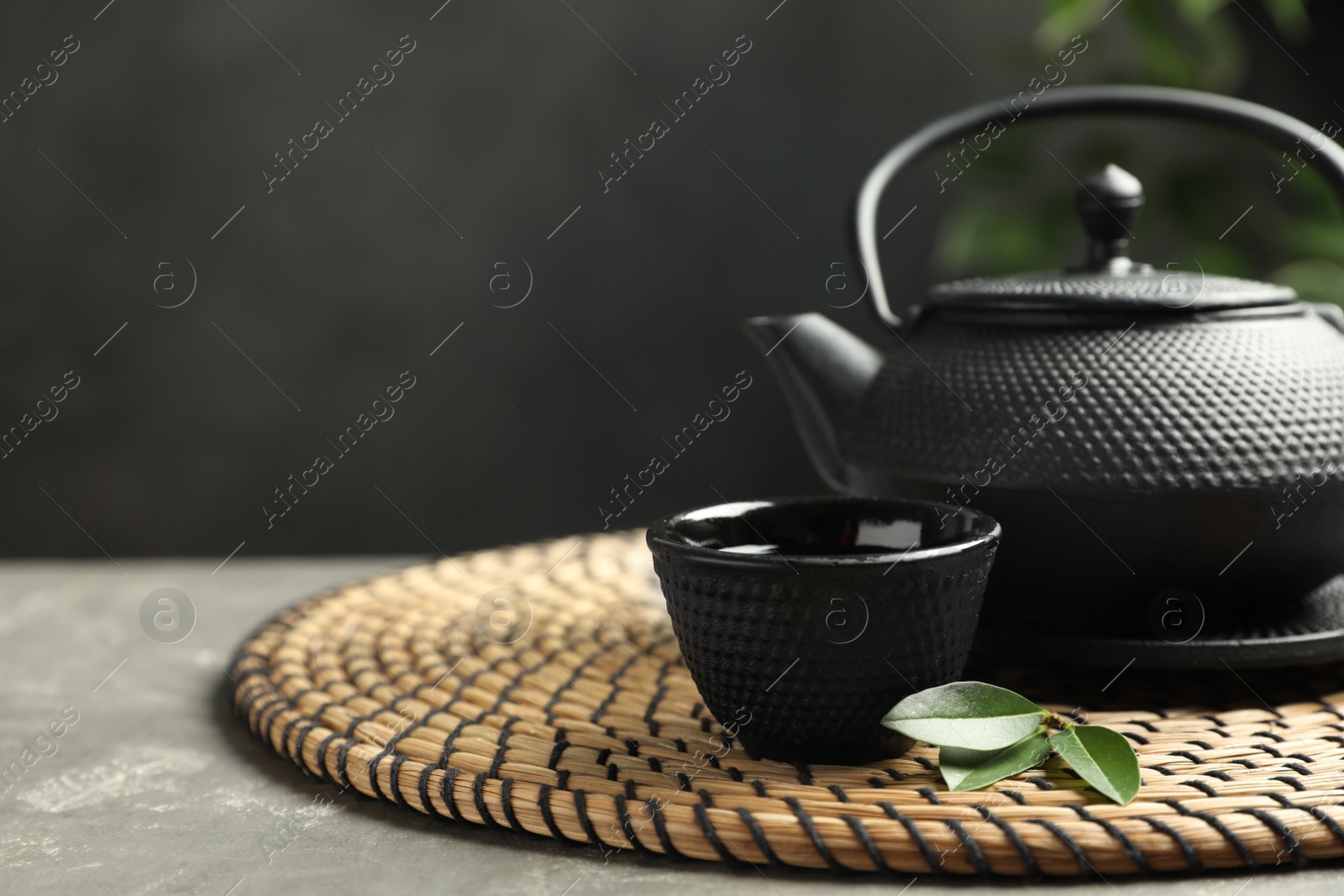 Photo of Cup and teapot of hot aromatic beverage on grey table. Space for text