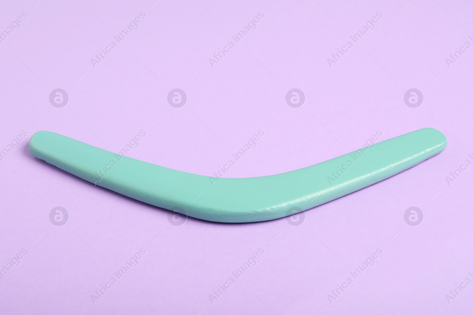 Photo of Turquoise boomerang on lilac background. Outdoor activity