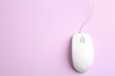 Modern wired optical mouse on lilac background, top view. Space for text