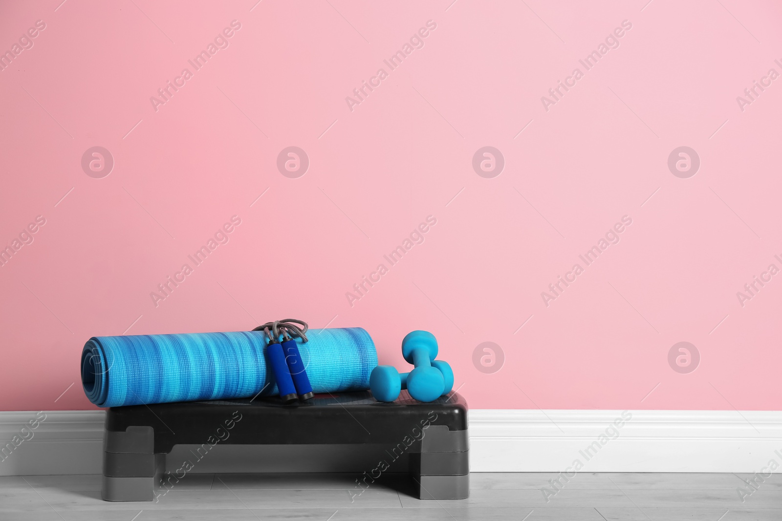 Photo of Set of fitness inventory on floor near color wall. Space for text